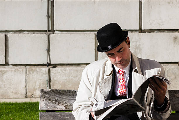 man in blue shirt and cap sitting on bench in park and reading a book