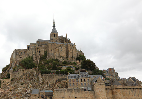 Beauvoir, France.  May 12, 2019.  Full view of the castle at Mont St. Michel with tourists milling around on the beach.