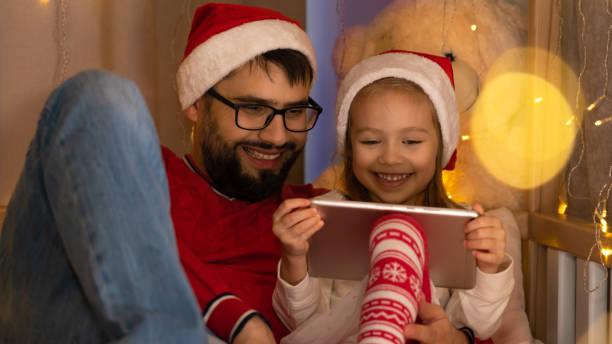 padre e hija usan tableta y se ríen. vacaciones de navidad de año nuevo - child 4 5 years laughing little girls fotografías e imágenes de stock
