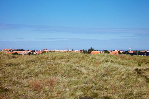 Field with town houses against blue sky