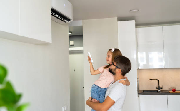 Family, father and child turn on air conditioner using remote control Family, father and child turn on air conditioner using remote control on background of light interior of apartment. air conditioner family stock pictures, royalty-free photos & images