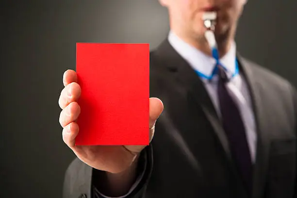 Photo of Businessman blows whistle and shows red card