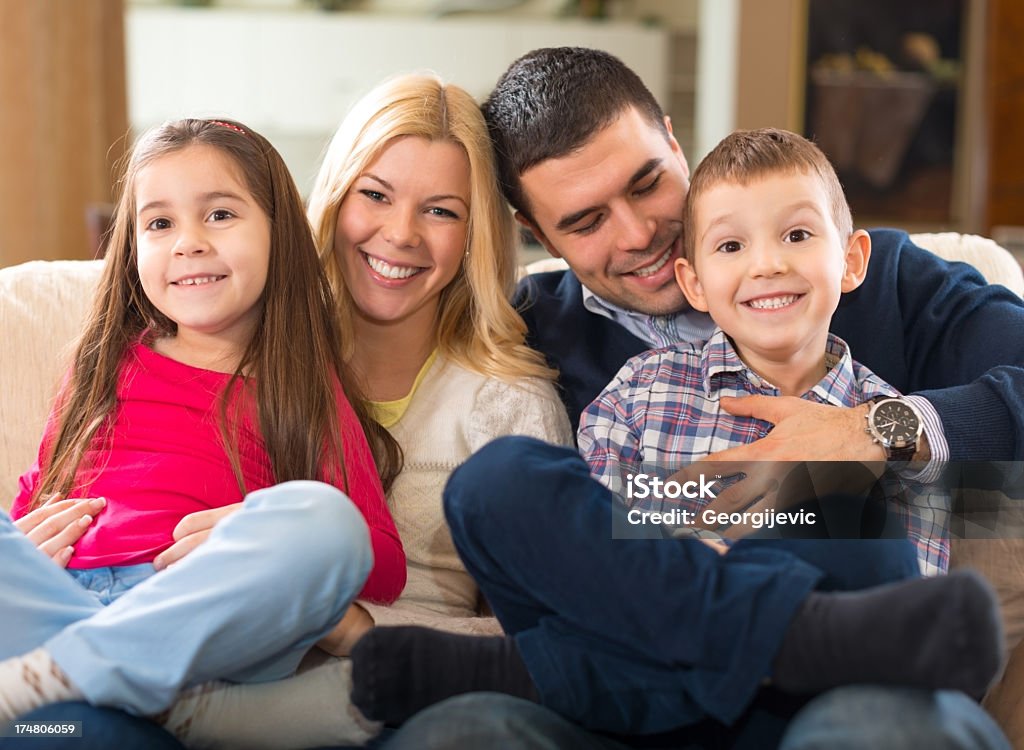 Famiglia felice nel soggiorno - Foto stock royalty-free di Abbigliamento casual