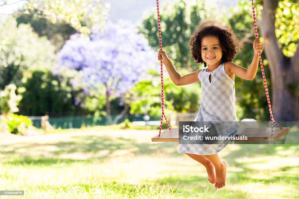 Sorridente jovem garota em um balanço no parque - Foto de stock de Criança royalty-free