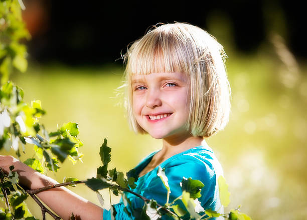 Portrait of a girl standing in a forest in a white dress looking at the camera