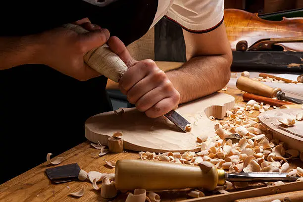 Instrument maker carving a new violin body in studio,