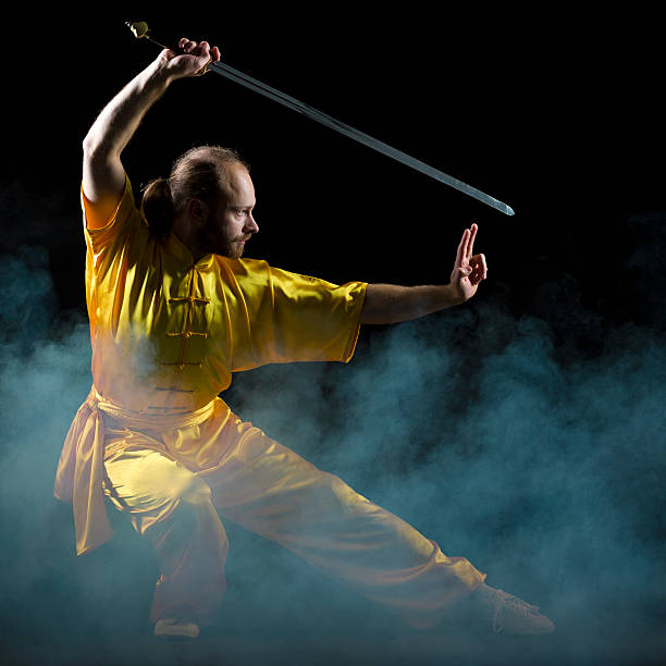 kung fu fighting position mit jian schwert auf dunklem hintergrund - wushu action aggression power stock-fotos und bilder