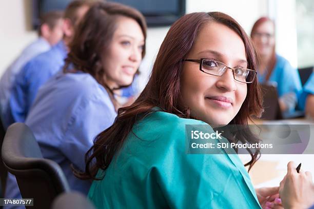 Jovem Hispânico Enfermeira Olhando Para Trás Durante A Reunião Da Equipe Médica - Fotografias de stock e mais imagens de Profissional de enfermagem