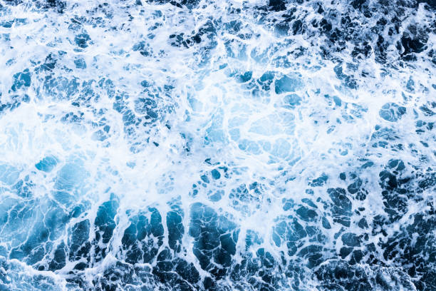 istock High angle view of a blue abstract background with sea foam design. Drone pointing view 1748080475