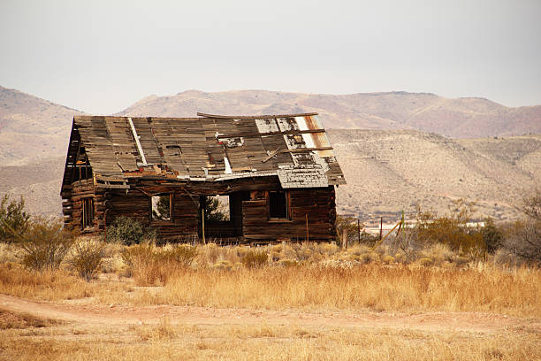 An old pioneer log cabin in Arizon with the Bradshaw Mountains in the background.