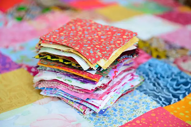 Pile of different colour and patterned material patches for a patchwork quilt.