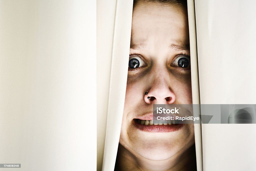 Verängstigt junge brunette Frau geschehen durch Vorhänge, Grimassieren - Lizenzfrei Abgeschiedenheit Stock-Foto