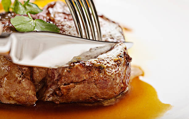 istock Knife and fork slice perfectly-grilled fillet steak 174808441