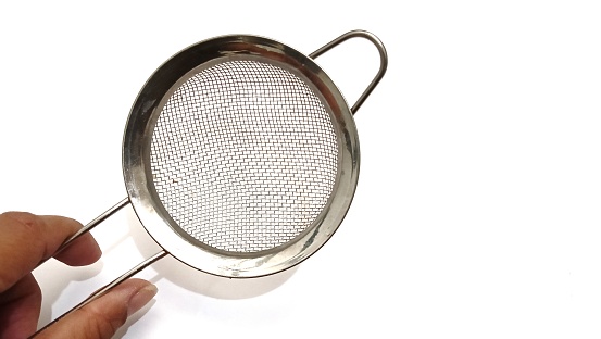 Hand holding food strainer or fine mesh strainer or stainless steel strainers on white background. Copy space.
