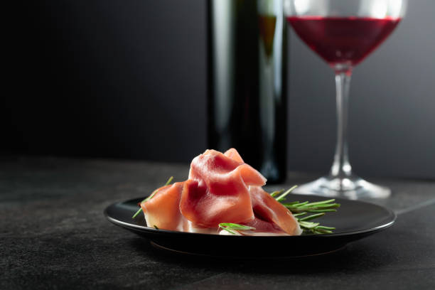 istock Prosciutto with rosemary and red wine on a black background. 1748095474