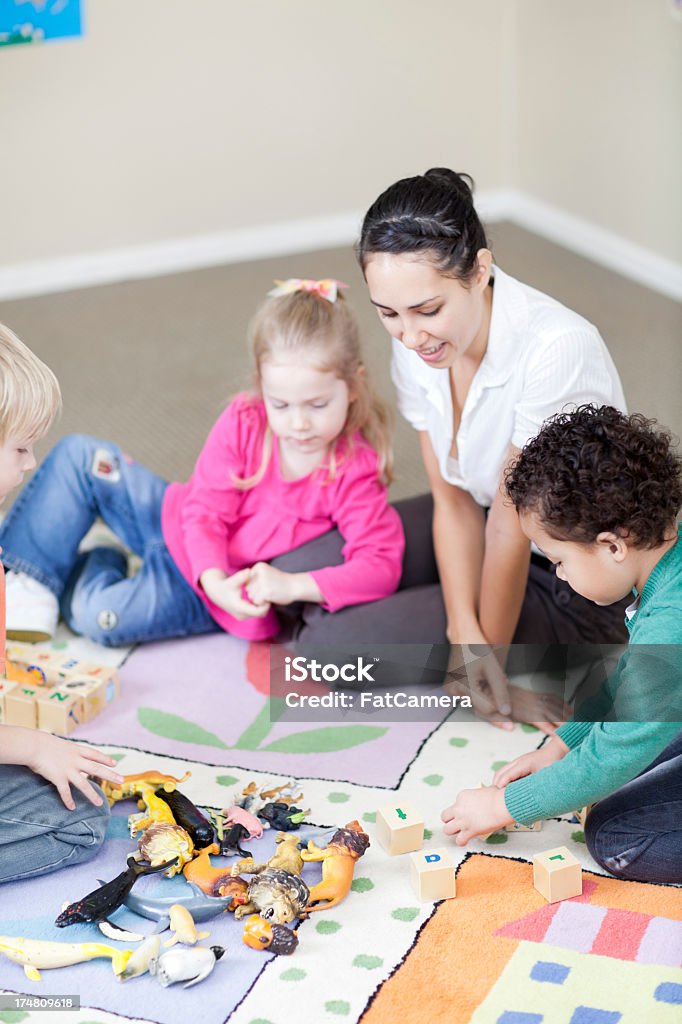 Insegnante e bambini in strutture di assistenza diurna - Foto stock royalty-free di A forma di blocco