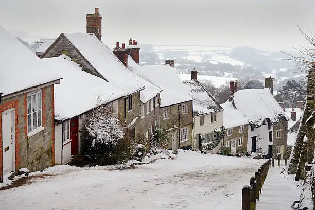 "The famous view of Gold Hill in Shaftesbury on a bleak cold mid -winter January day in the snowDorset, UK"