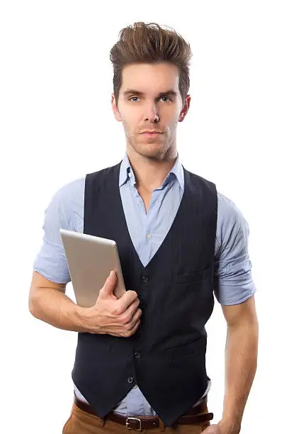A young attractive man stands in casual clothing holding his tablet computer