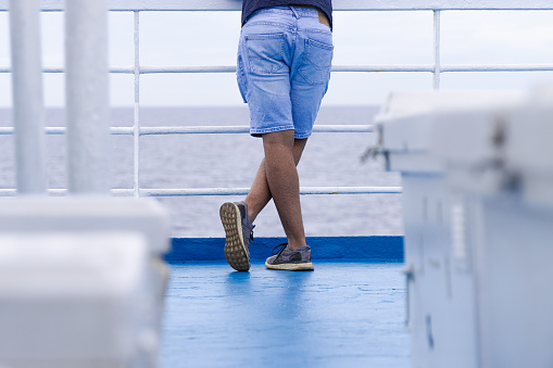 Low angle photo of a caucasian man with short jeans and sneakers on a blue floor
