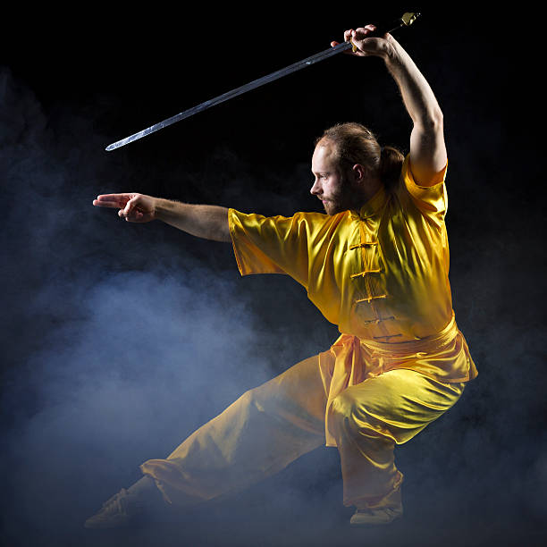 kung fu fighting position mit jian schwert auf dunklem hintergrund - wushu action aggression power stock-fotos und bilder