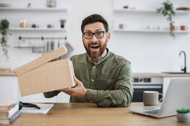 istock Excited blogger sitting at desk with cardboard box in hands 1748098887