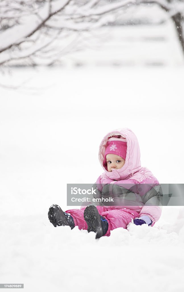 Маленькая девочка сидит в снегу - Стоковые фото 12-17 месяцев роялти-фри