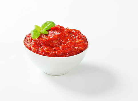 fresh tomato sauce with a basil in a white bowl