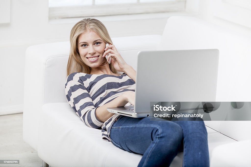 Joven hermosa mujer rubia que descansan en el sofá con el ordenador portátil - Foto de stock de 20-24 años libre de derechos