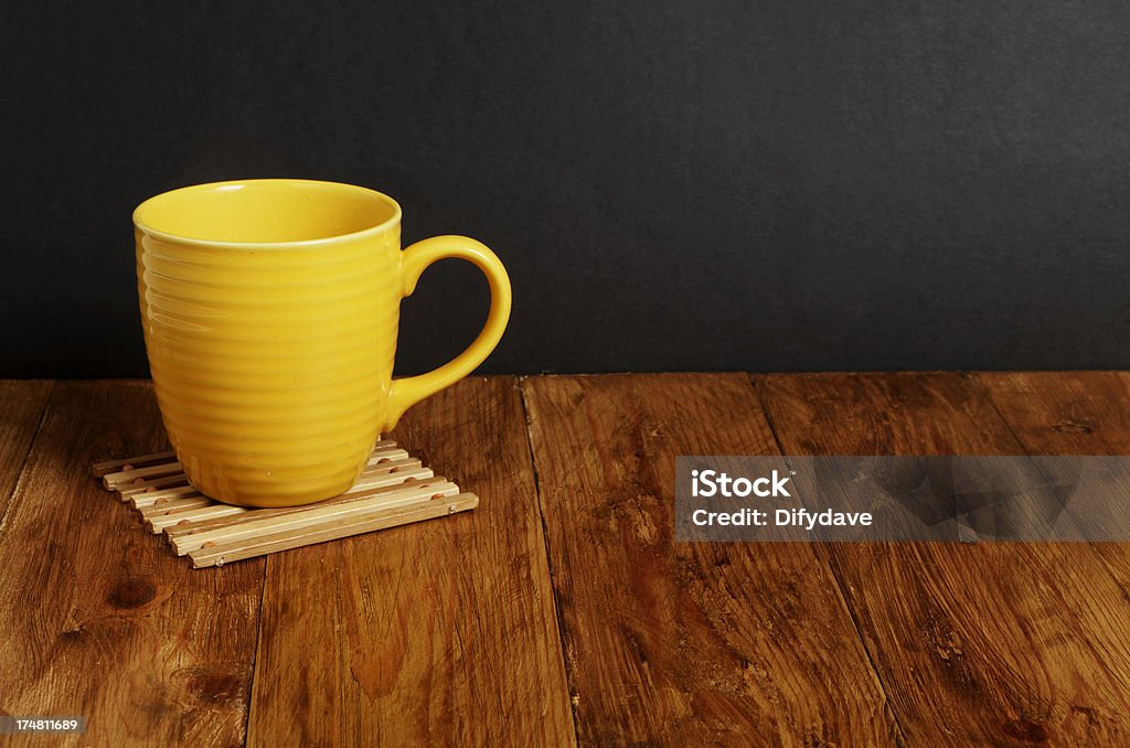 Amarillo taza en la superficie de madera con fondo oscuro - Foto de stock de Alfarería libre de derechos