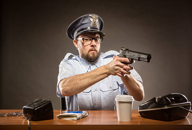 funcionario jefe de policía de sujeción de pistola inicia mientras que en la recepción - desk police police station humor fotografías e imágenes de stock