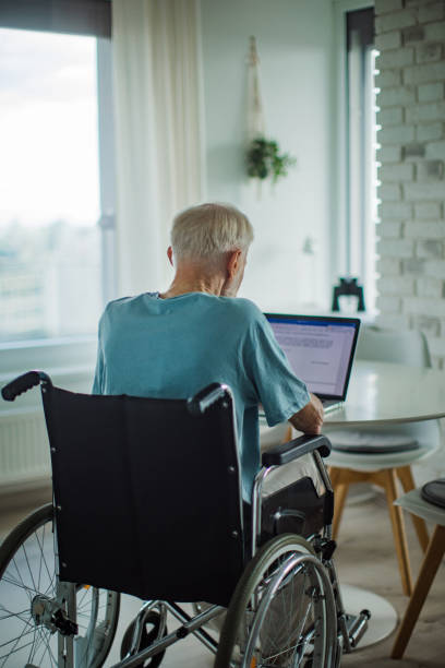 istock Senior man in a wheelchair write document on laptop. Elderly man using digital technologies, working on a notebook. Concept of seniors and digital skills. 1748135005