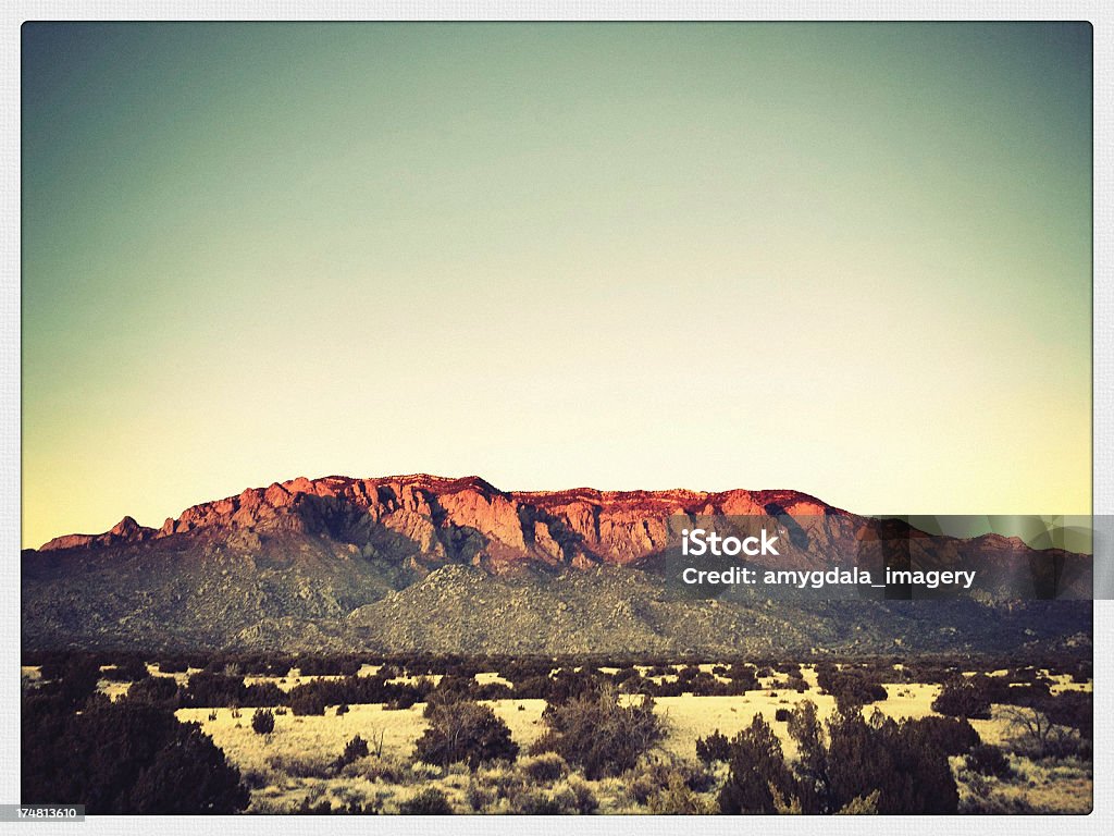 mobilestock mountain sunset "orange alpenglow illuminates a mountain ridge with peaks above a desert meadow filled with juniper trees.  a moody clear sky stands watch from above.  such beautiful and peaceful nature scenery can be found in the sandia mountains of albuquerque, new mexico.  horizontal mobilestock composition with retro color treatment and border." Albuquerque - New Mexico Stock Photo