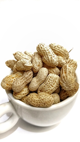 collection of roasted peanuts in white bowl. healthy snacks for the heart. white background. copy space,