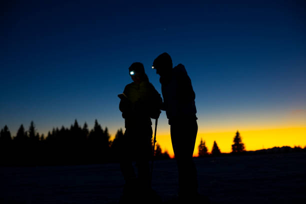 istock Two women skiers with flashlight on forehead using mobile phone in snow 1748137264