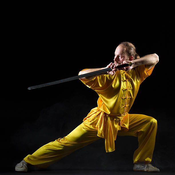kung fu fighting posizione con jian spada su sfondo scuro - self defense wushu action aggression foto e immagini stock