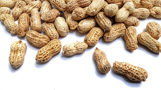 pile of roasted peanuts on white background. healthy snacks for the heart.