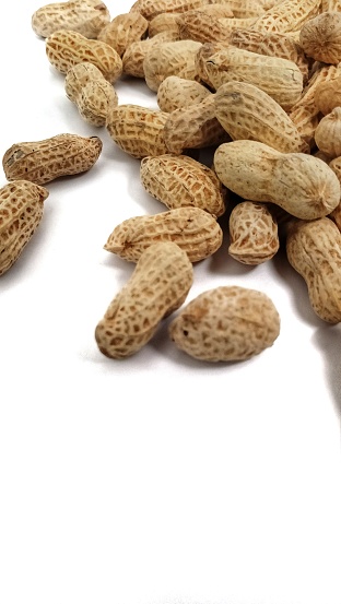 pile of roasted peanuts on white background. healthy snacks concept. copy space.