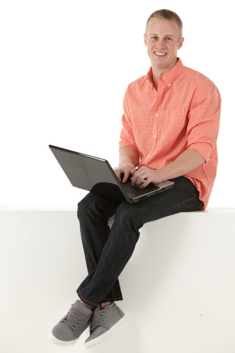 Man sitting on a ledge and using laptop