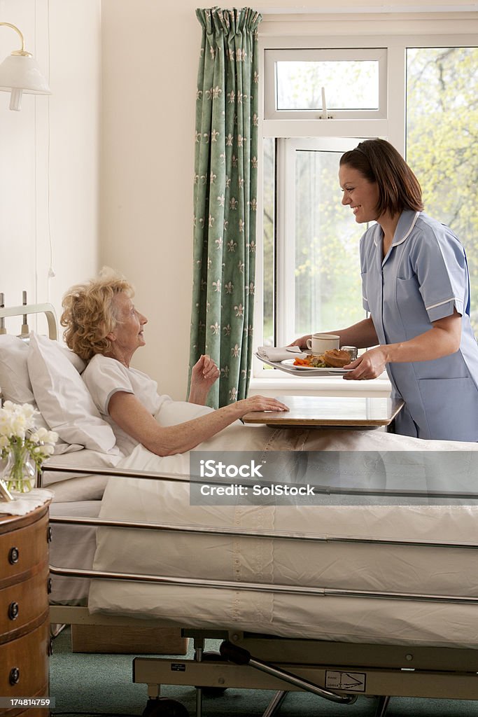 Nurse serving lunch Nurse serves lunch to elderly to elderly lady . Bed - Furniture Stock Photo