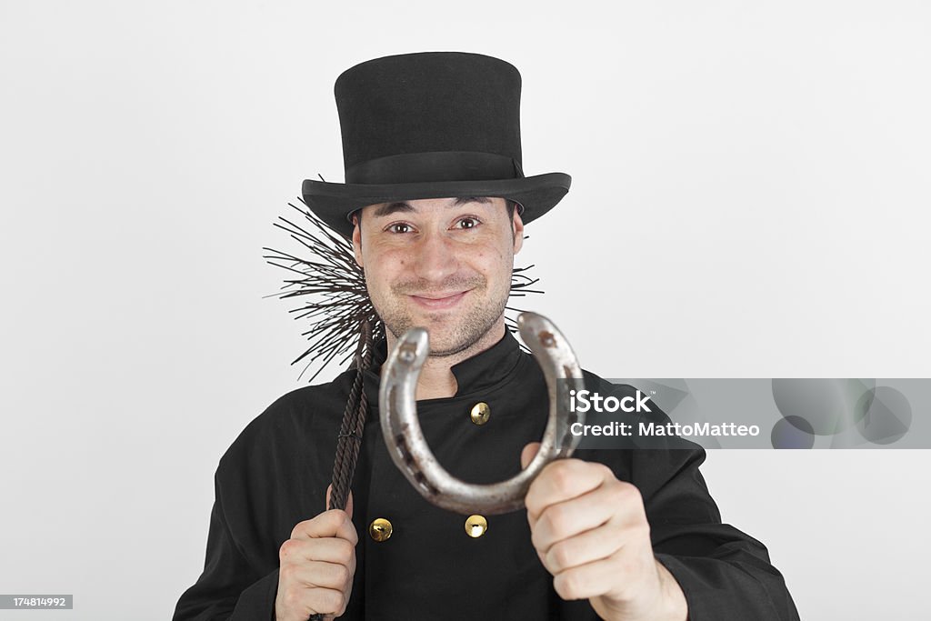 Young chimney sweep with a horseshoe A young chimney sweep in front of a grey background is holding a cloverleaf Chimney Sweep Stock Photo