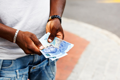 A man's hands holding a bundle of the new South African Hundred Rand notes - featuring iconic statesman Nelson Mandela.