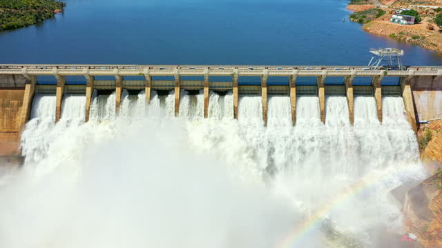Drone, dam and lake of water with rainbow for power production, renewable energy or sustainable electricity in nature. Hydroelectric, bridge and aerial view of river, waterfall or flood gate outdoor