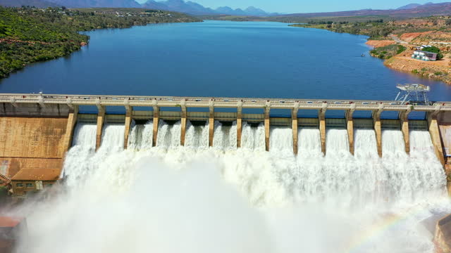 Dam, infrastructure and water from river with drone in nature, environment and rural landscape. Above, lake wall and waterfall with spray, splash or clean energy from flood and falling liquid stream