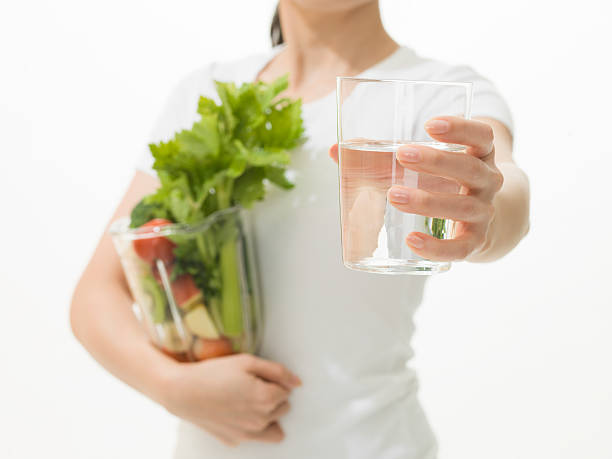 femme tenant une tasse d'eau et de légumes presse-citron - green smoothie vegetable juice fruit photos et images de collection
