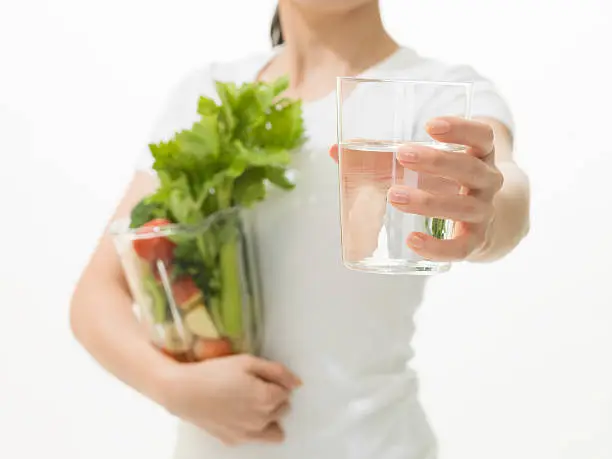 Photo of Woman holding a cup of water and Vegetable juicer