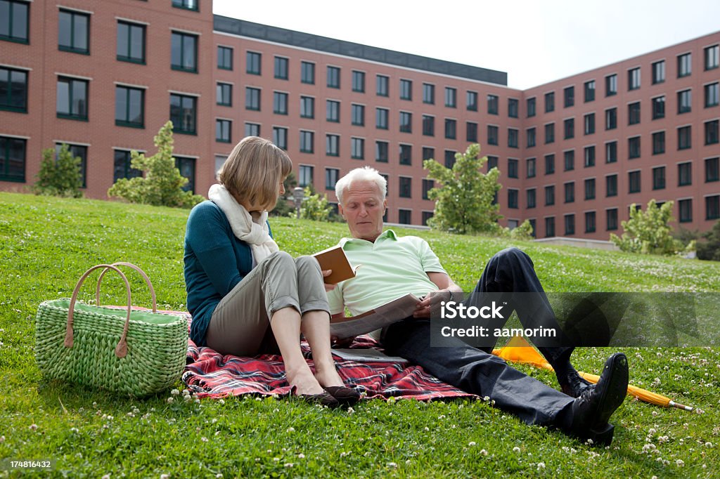 Coppia Senior leggendo nel parco - Foto stock royalty-free di 55-59 anni