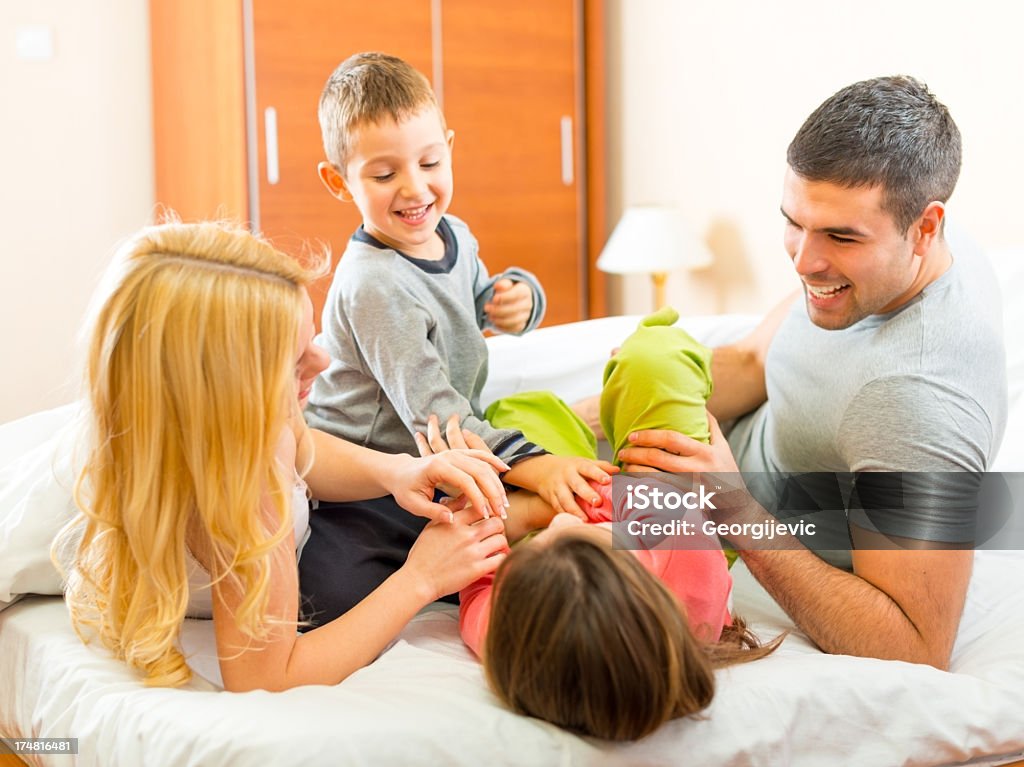 Família jogando juntos na cama - Foto de stock de 25-30 Anos royalty-free