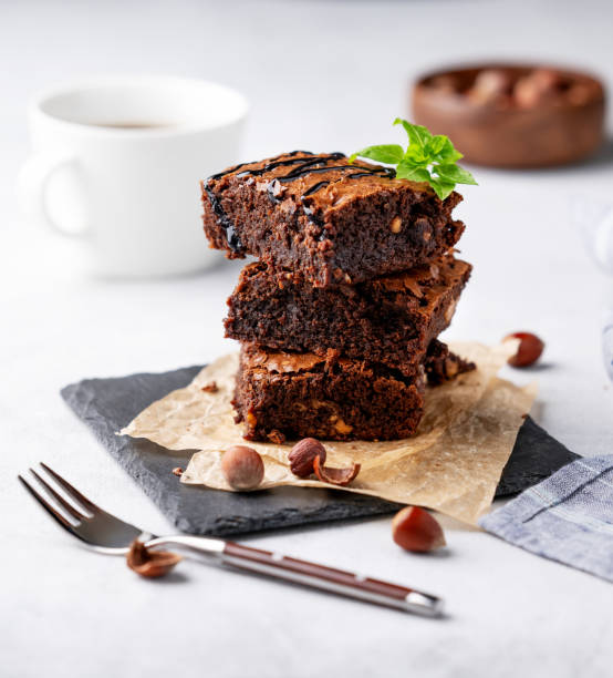 istock A stack of chocolate brownies with mint, hazelnuts and salted caramel on baking paper on a light background with a cup of coffee. 1748164881