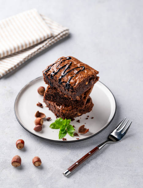 istock A stack of chocolate brownies with mint, hazelnuts and salted caramel on a white plate on a light background with napkin. 1748165418