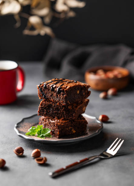 istock A stack of chocolate brownies with mint and  hazelnuts on a dark  background with cup of coffee and nuts. 1748165942